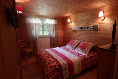 Chambre en bois, lit double, commode de rangement,fenêtre donnant sur des arbres, aucun vis à vis